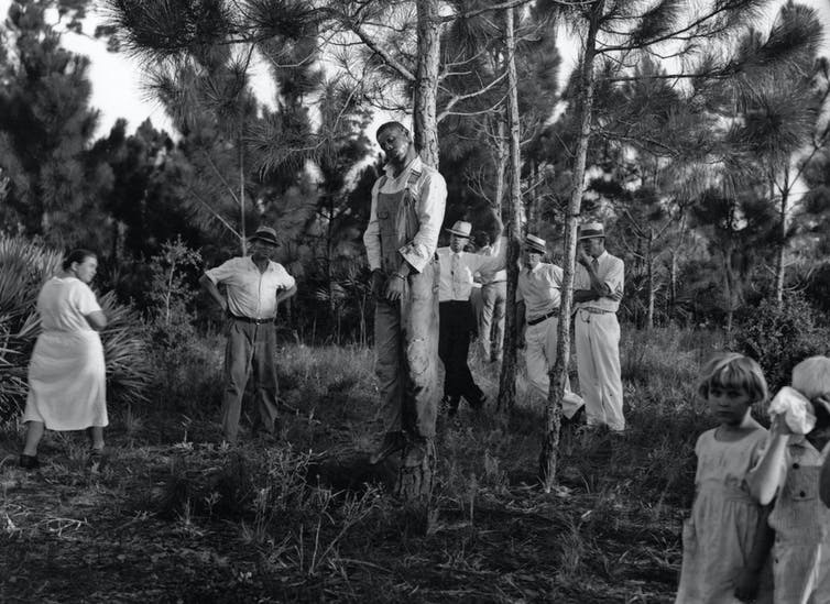 The body of Rubin Stacy, 32, hangs from a tree in Fort Lauderdale, Florida, as neighbors visit the site July 19, 1935. White lynchings of blacks were common during the era